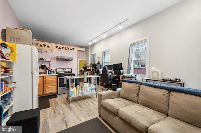 living room with rail lighting, a wall mounted AC, and light hardwood / wood-style floors