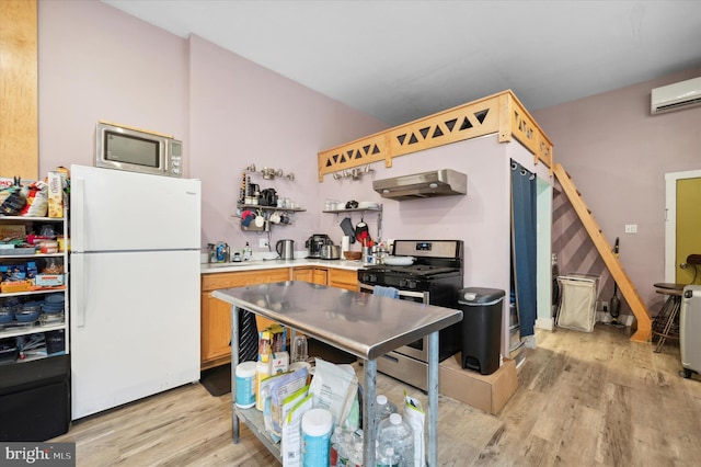 kitchen with appliances with stainless steel finishes, a wall mounted air conditioner, and light hardwood / wood-style flooring