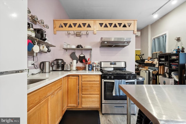 kitchen with extractor fan, light wood-type flooring, white refrigerator, track lighting, and stainless steel range with gas cooktop