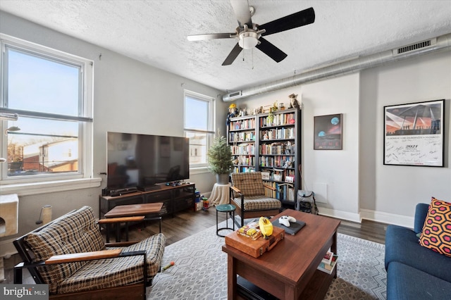 living room with ceiling fan, dark hardwood / wood-style floors, and a textured ceiling