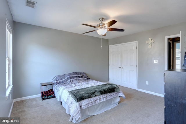 carpeted bedroom featuring multiple windows, ceiling fan, and a closet