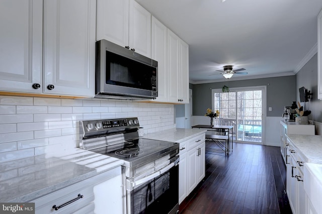 kitchen with white cabinetry, ornamental molding, dark hardwood / wood-style flooring, ceiling fan, and stainless steel appliances