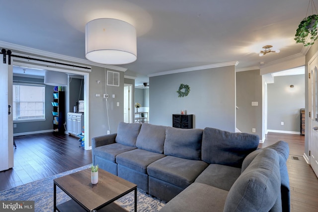 living room featuring crown molding, a barn door, and dark hardwood / wood-style flooring