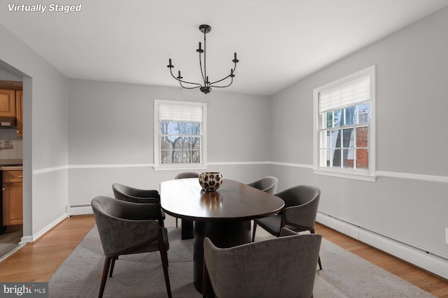 dining room with a baseboard radiator, a wealth of natural light, and light wood-type flooring