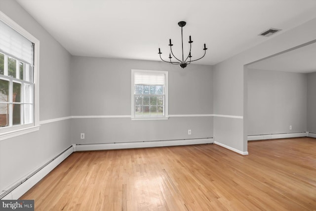 empty room featuring an inviting chandelier, hardwood / wood-style floors, and a baseboard heating unit