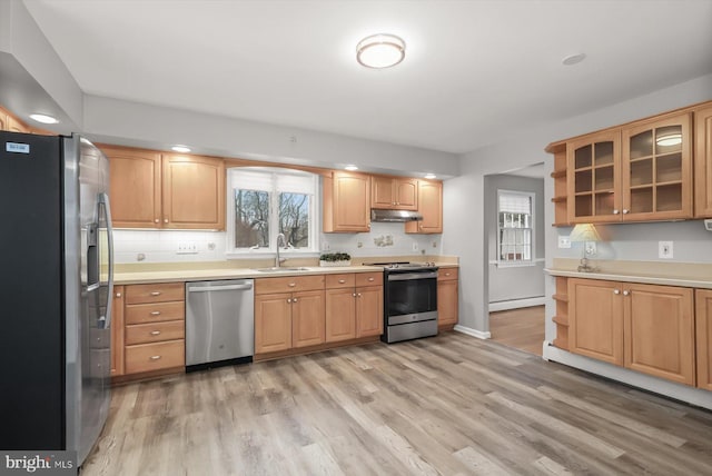 kitchen with sink, baseboard heating, appliances with stainless steel finishes, decorative backsplash, and light wood-type flooring