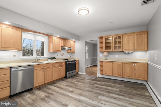 kitchen featuring stainless steel appliances, sink, baseboard heating, and light wood-type flooring