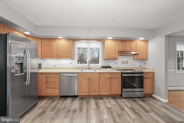 kitchen featuring sink, light hardwood / wood-style flooring, backsplash, a baseboard heating unit, and stainless steel appliances