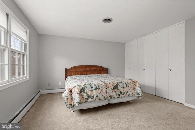 carpeted bedroom with baseboard heating and a closet