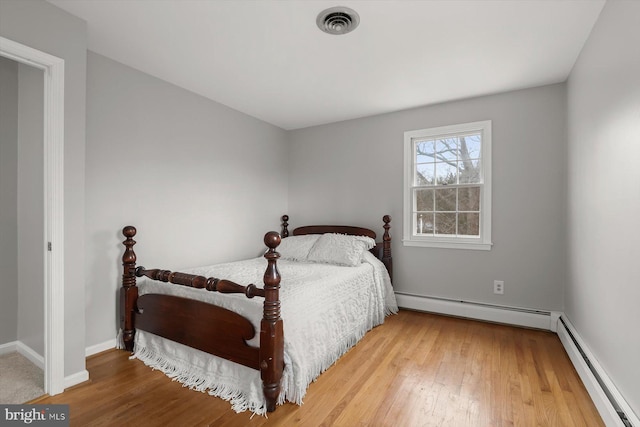 bedroom with a baseboard radiator and wood-type flooring