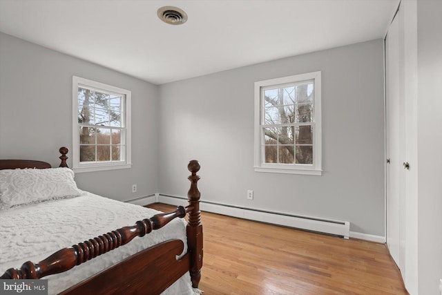 bedroom with hardwood / wood-style floors and baseboard heating