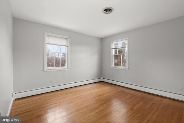 unfurnished room featuring light hardwood / wood-style flooring, a baseboard radiator, and a healthy amount of sunlight