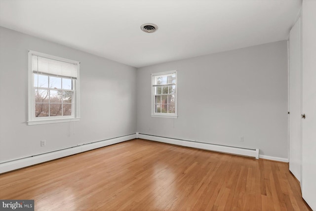 spare room featuring a baseboard radiator and light hardwood / wood-style floors