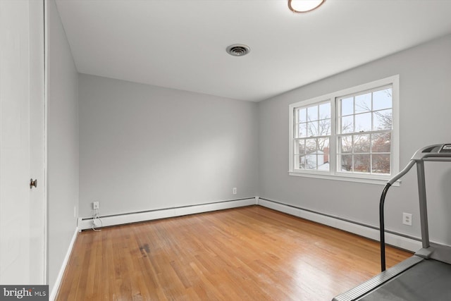 empty room featuring a baseboard heating unit and light hardwood / wood-style floors