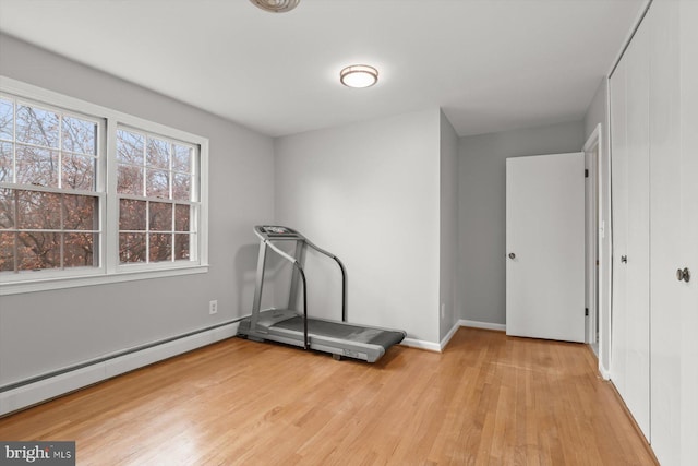 workout room with a baseboard heating unit and light hardwood / wood-style floors