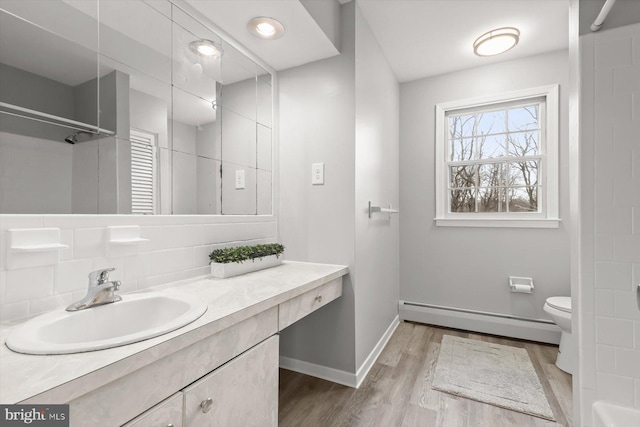 bathroom featuring hardwood / wood-style flooring, baseboard heating, vanity, a shower, and toilet