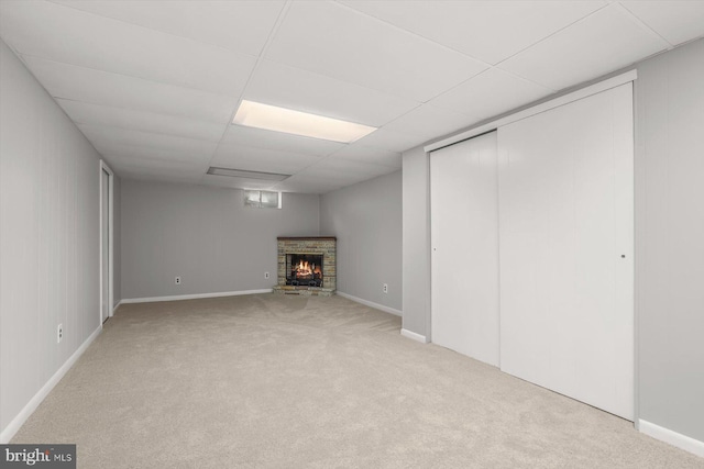 basement with a paneled ceiling, light colored carpet, and a fireplace