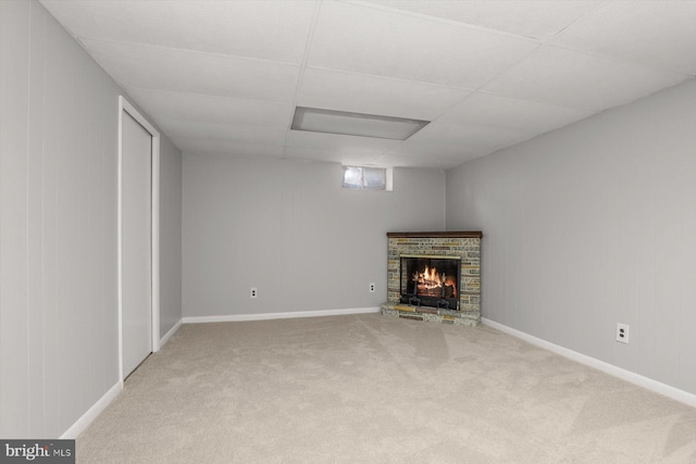 basement with a brick fireplace, carpet floors, and a paneled ceiling