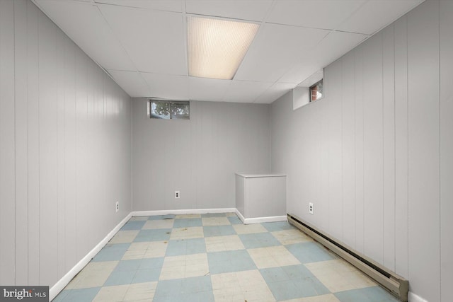 basement with a baseboard radiator and a paneled ceiling