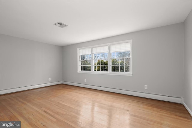 empty room with a baseboard heating unit and light hardwood / wood-style flooring