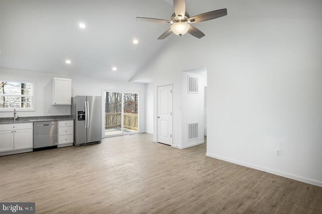 kitchen featuring appliances with stainless steel finishes, high vaulted ceiling, sink, white cabinets, and light wood-type flooring