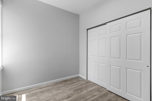 unfurnished bedroom with a closet and light wood-type flooring