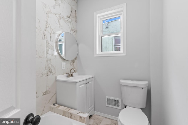 bathroom with vanity, a tub, and toilet