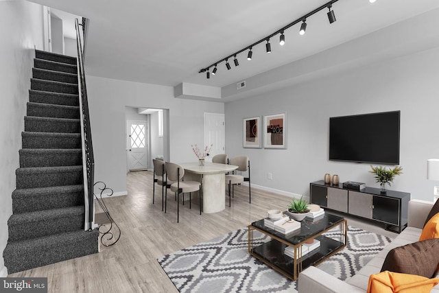 living room with light hardwood / wood-style flooring and track lighting