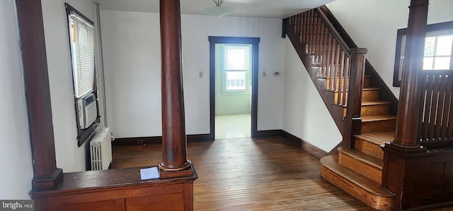 foyer entrance featuring radiator, dark wood-type flooring, and ornate columns