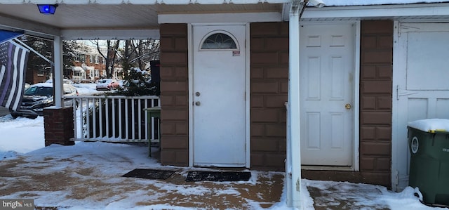 snow covered property entrance featuring covered porch