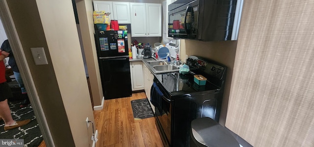 kitchen featuring sink, black appliances, white cabinets, and light wood-type flooring