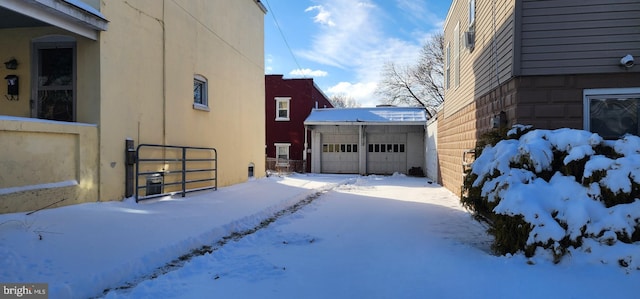 snow covered property with a garage and an outdoor structure