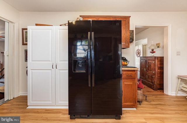 kitchen with light hardwood / wood-style flooring and black refrigerator with ice dispenser