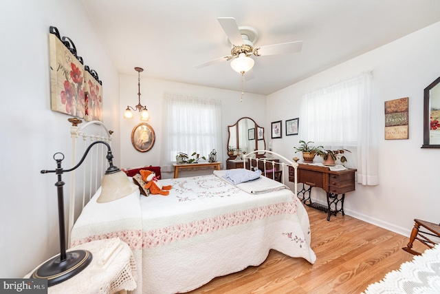 bedroom featuring ceiling fan with notable chandelier and hardwood / wood-style floors