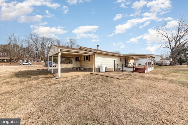 back of property with a carport, a lawn, and a patio area