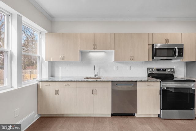 kitchen with light brown cabinetry, sink, light stone counters, light hardwood / wood-style flooring, and stainless steel appliances