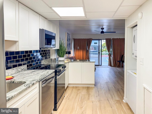 kitchen with stacked washer and dryer, light hardwood / wood-style flooring, ceiling fan, stainless steel appliances, and white cabinets