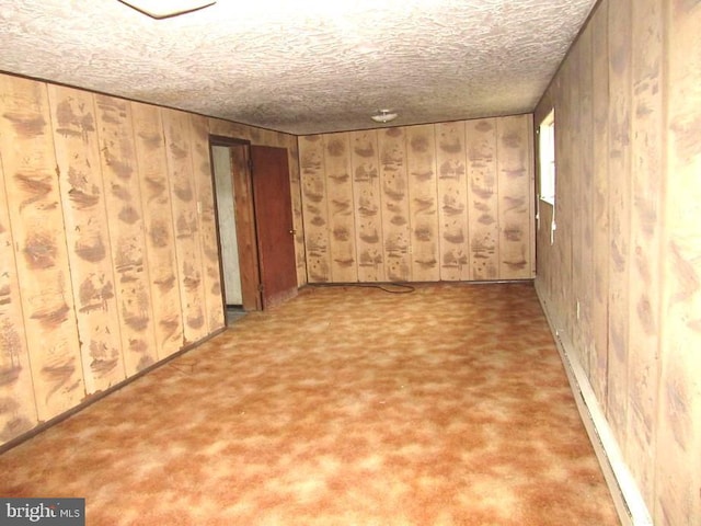 spare room with wooden walls and a textured ceiling