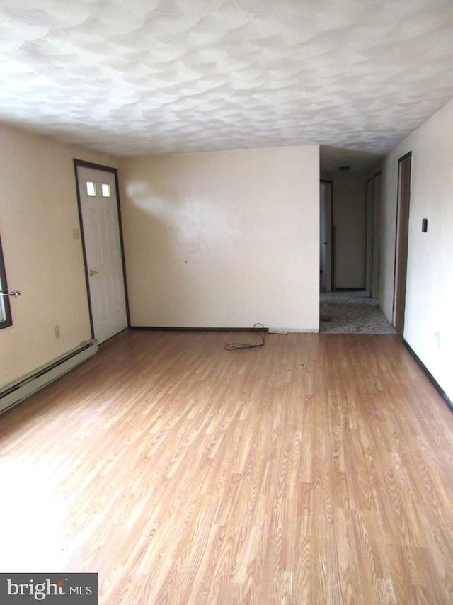 empty room with a baseboard heating unit and light hardwood / wood-style floors