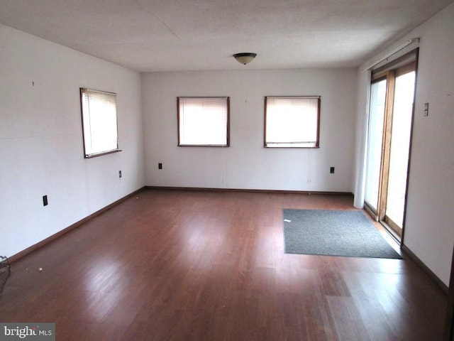 unfurnished room with dark wood-type flooring and a wealth of natural light