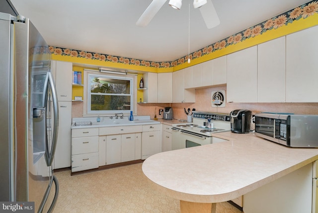 kitchen with sink, stainless steel appliances, kitchen peninsula, and white cabinets