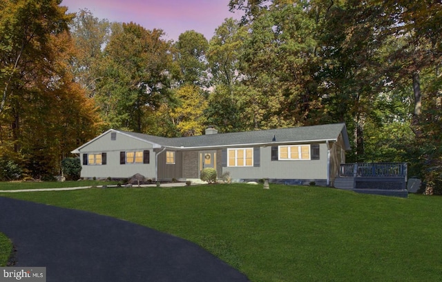 ranch-style house featuring a lawn and a deck