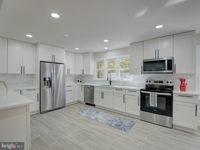 kitchen with sink, white cabinets, backsplash, stainless steel appliances, and light stone countertops