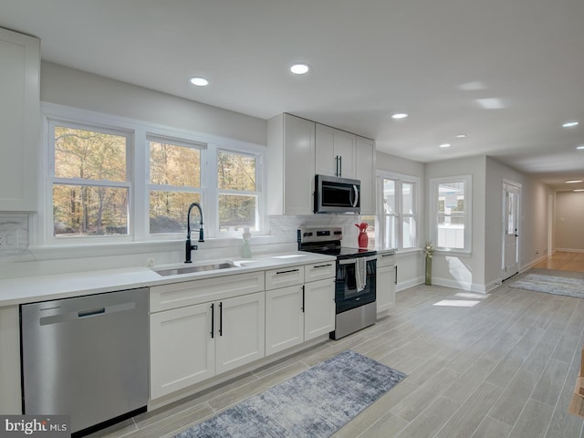 kitchen with white cabinetry, sink, tasteful backsplash, and stainless steel appliances