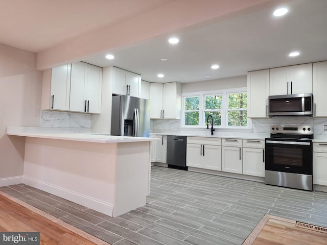 kitchen featuring appliances with stainless steel finishes, white cabinets, and kitchen peninsula