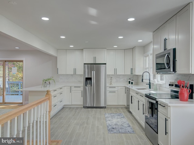 kitchen featuring white cabinetry, appliances with stainless steel finishes, kitchen peninsula, and sink