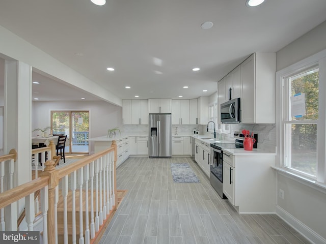 kitchen featuring stainless steel appliances, white cabinetry, sink, and decorative backsplash