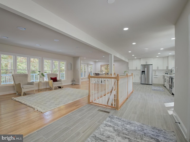 interior space featuring white cabinetry, decorative backsplash, stainless steel appliances, and light hardwood / wood-style floors