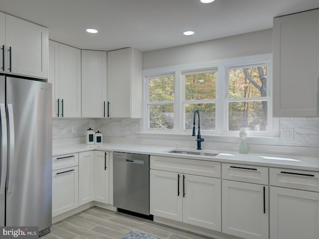 kitchen featuring stainless steel appliances, sink, white cabinets, and backsplash