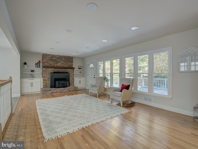 unfurnished living room with light hardwood / wood-style floors and a brick fireplace